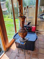 vase with tulips placed on metal stand near window