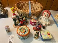 Full lot overview showing figurines, tins, snow globe, doll and basket