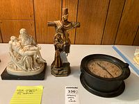 Pieta figurine, crucifixion figure, black round clock displayed together