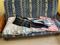 Stack of five blankets on futon showing overall colors and types