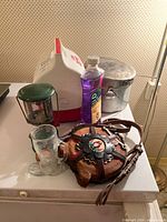 Overall lot showing cooler, lantern, pot, lamp oil, glass mug, leather canteen
