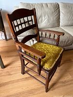 Angled view of entire wooden armchair with upholstered seat