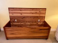 Front view of open cedar chest showing interior, lid, casters
