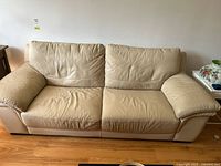 Front view of beige leather couch showing full width and cushions