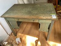 Top and front view of wooden desk showing surface wear and drawer