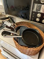 Assorted frying pans inside wicker pet bed