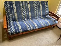 Front view of futon showing wood arms, blue patterned cushion