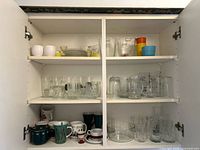 Full view of cabinet shelves with glassware, mugs, bowls and pitchers