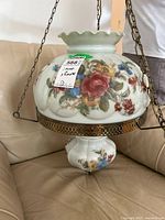 Front view of vintage floral printed glass hanging ceiling fixture with large upper and smaller globe shade suspended by chains.