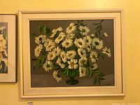 Full view of framed oil painting showing white daisies in green vase on grey background.