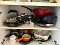 Two shelves of assorted cookware and tools