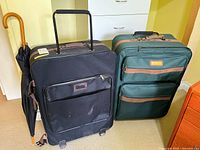 Green Sergio Valente suitcase, black suitcase, umbrella grouped together