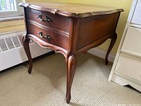 Front view of wooden side table showing two drawers and cabriole legs