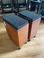 Both Sonab OA-116 speakers showing wood veneer cabinets and caster bases