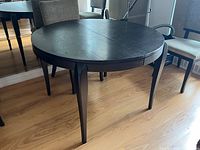 Full view of dark round wood dining table showing legs and top