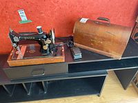 Singer sewing machine on table with wooden case and foot pedal