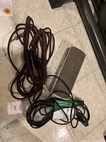 Photo of Ernie Ball passive volume pedal with accompanying cables on floor showing pedal top and wire bundle.