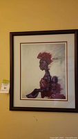 Full view of framed African art painting of a woman with a child on her back, in profile.