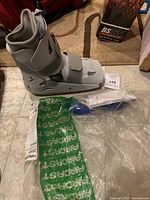 Gray Aircast medical walking boot with adjustable straps, alongside a blue pump and clear package with Aircast branding for foam liners.