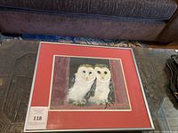 Framed painting showing two barn owls sitting together on a ledge inside a window frame.