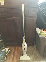 Full view of the white upright Bissell Featherweight vacuum cleaner standing upright with cord wrapped around the back.