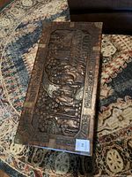 Top-down view of lid showing intricate hand-carved relief scene