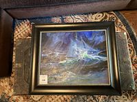 Framed painting showing ocean storm scene with dominant blue and green hues and a black frame with beaded inner edge.