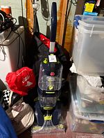 Full view of Hoover Power Path Pro XL carpet washer in basement setting with storage bins and bags nearby.