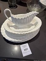 Side view of stacked white ironstone plates and gravy boat with scalloped edges
