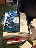 Stack of printing paper packs including PaperDirect letterhead and envelope boxes.