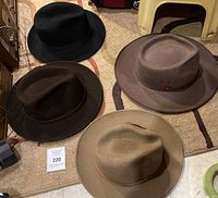 Top view photo of four men's felt hats laid on a carpet showing different colors and styles.