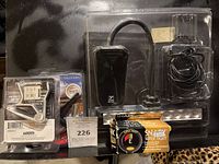 Various packaged guitar accessories shown on black surface: clip-on tuners, capo clamps, instrument cable, and guitar strings