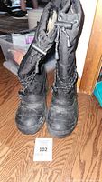 Front view of black Kodiak boots standing upright on wood floor showing laces and rugged soles.