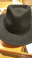Black Stetson wool hat shown sitting on a box. The hat is in good condition with minor lint or dust particles visible.