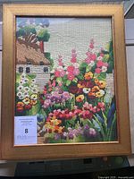 Full framed embroidery artwork showing a colorful garden and cottage scene.