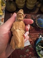 Hand holding a carved wooden maritime figure with detailed facial features and sailor cap