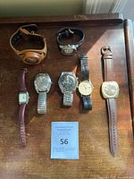 Overview of seven wristwatches on wooden surface