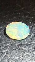 Oval faceted Ethiopian opal gemstone showing multicolored flash on black background