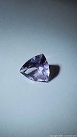 Photo showing the natural purple amethyst gemstone from an angled top view to highlight the trillion cut and clarity.