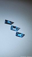 Three rectangular baguette cut natural blue topaz stones shown on a white background with shadows