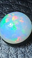 Top‐down view of oval opal cabochon on black textured background
