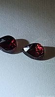 Two deep red pear-shaped spinel gemstones shown together on neutral background, exhibiting good clarity and faceted cuts.