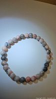 Front view of the stretchy bracelet showing the color and pattern of the pink Zebra Jasper beads in an oval shape.