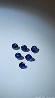 Six natural royal blue sapphires displayed on white background, round cut, about 2.8-3.1mm each.
