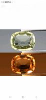 Two images showing the color change property of the cushion cut Turkish diopside gemstone; pale yellow-green under daylight and bright orange under incandescent light.