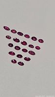 Top view of 20 marquis cut natural rubies arranged on white background showing color and size consistency.