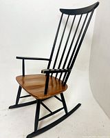 Angled side view showing teak seat, black painted spindle back and rockers