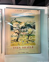 Full view of framed lithograph poster showing the artwork and text with reflections and gallery lighting.