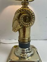 Close-up detail of the solid brass ram head base with polished finish and curled horns.