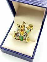 Ring in presentation box, showing dragon design and emerald stones